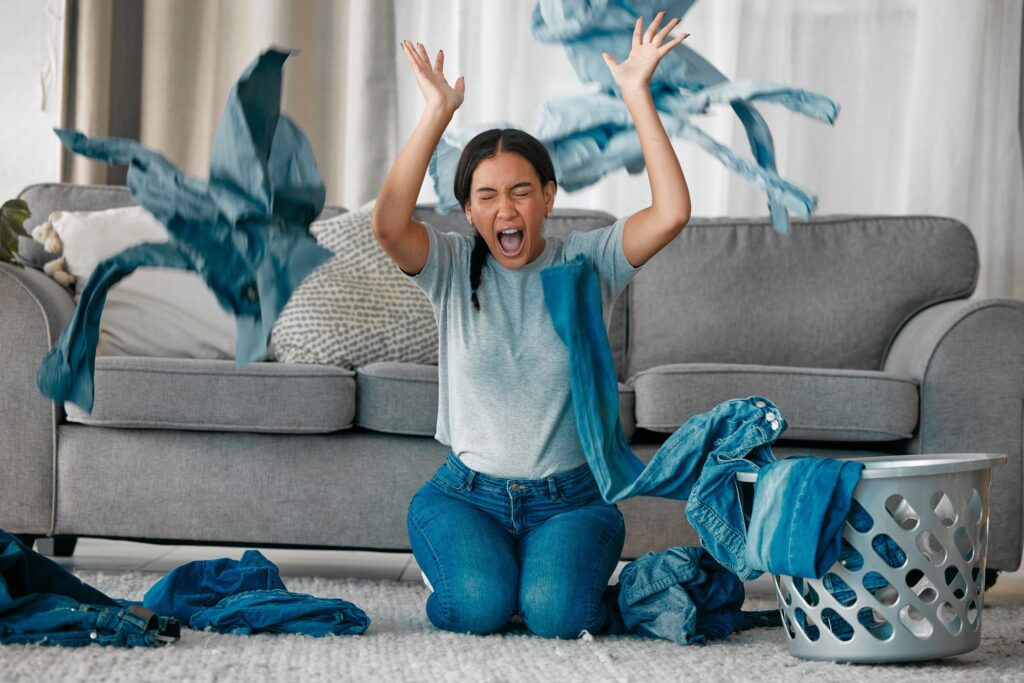 Laundry, angry and woman with clothes in air frustrated from cleaning, housekeeping and housework.