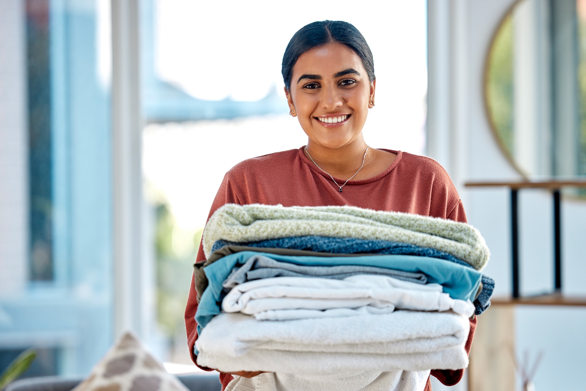 Portrait, cleaning or woman with laundry or happy smile after washing clothes or towels in cleaning