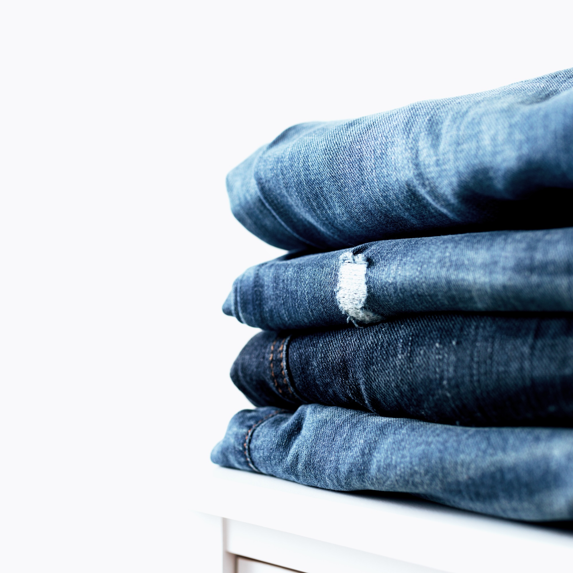 Stack of different jeans on the shelf or table